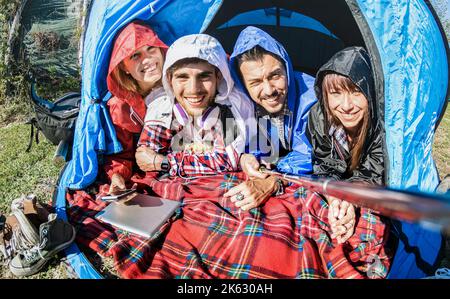 Le coppie migliori amici che prendono selfie alla tenda del campeggio il giorno di sole dopo la pioggia - concetto della gioventù e della libertà all'aperto in vacanza di pausa primaverile - giovane p Foto Stock