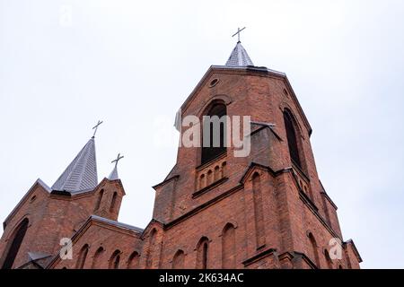 Brest, Bielorussia - 5 giugno 2022: Chiesa cattolica con vista in mattoni rossi dal basso verso il cielo illuminato Foto Stock