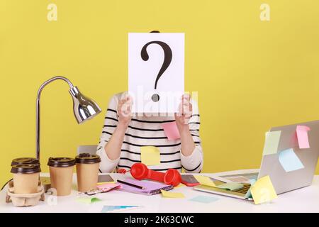 Donna anonima coperta di note appiccicose che nascondono il volto dietro il white paper con punto interrogativo, trovare una soluzione intelligente, chiedere consiglio. Studio interno girato isolato su sfondo giallo. Foto Stock