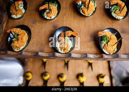 Tavolo per banchetti splendidamente decorato con vari antipasti di pesce e sandwich e antipasti di gamberi Foto Stock