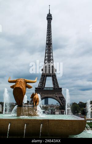 Uno scatto verticale di una bella fontana d'acqua con sculture di bue e la famosa torre Eiffel contro un cielo nuvoloso Foto Stock