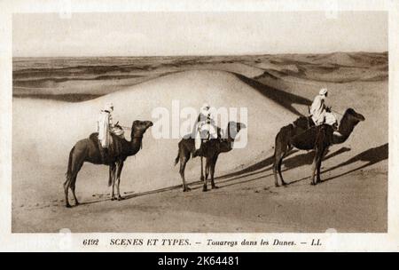 Tuareg nomadi in sella a cammelli tra le dune sahariane - Nord Africa. Foto Stock