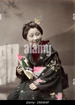 Vintage 19 ° secolo fotografia Giappone - giovane donna in ornato kimono, sorridente. Foto Stock