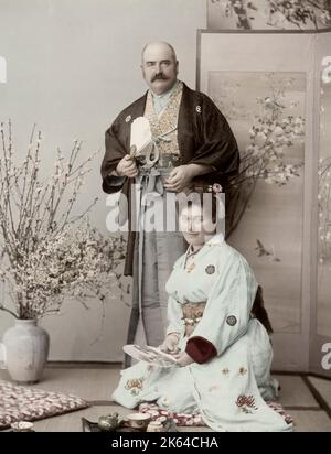 Fotografia d'epoca del XIX secolo - epoca Meiji Giappone: Ritratto di una coppia occidentale vestita di abiti giapponesi in un ambiente stduio, probabilmente turisti. Foto Stock