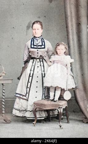 Una ragazza vittoriana di classe superiore, Beatrice (Emily Beatrice Violet, d 1930), in piedi su una sedia, con la sua tata in piedi accanto a lei. Vivevano a Howbury Hall, Renhold, Bedfordshire. Foto Stock