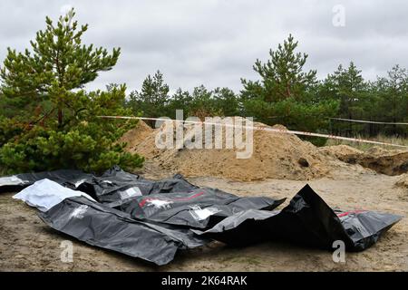 Lyman, Donetsk, Ucraina. 11th Ott 2022. Borse di plastica con i corpi si trovano sul terreno come membri di una squadra forense lavorare ad un exhumation in una tomba di massa a Lyman. Nell'ambito di una rapida controffensiva Ucraina che ha ricattato dal controllo russo alcune zone delle regioni di Donetsk, Kharkiv e Kherson, è stata liberata anche Lyman. La distruzione a Lyman, una ferrovia principale e un centro di transito, è così diffusa che grandi parti della città sono state completamente distrutte. Credit: ZUMA Press, Inc./Alamy Live News Foto Stock