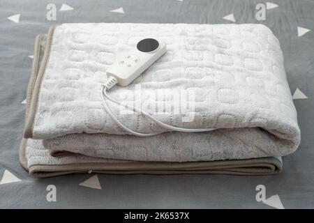 coperta elettrica ripiegata con controller sul letto a composizione orizzontale Foto Stock