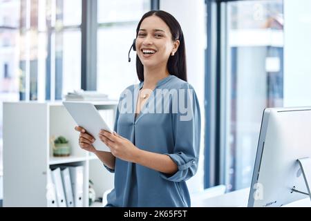 Shes sempre progettando qualcosa. Ritratto di un giovane operatore del call center che lavora su un tablet digitale in ufficio. Foto Stock