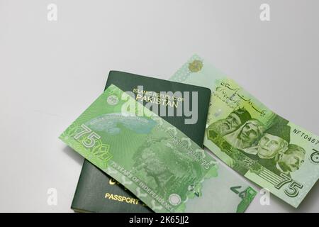 Nuova banconota da 75 rupie pakistane con passaporto pakistano su sfondo bianco isolato Foto Stock