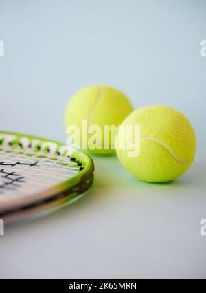Sport, tennis ball e racchetta in uno studio vuoto su sfondo grigio per lo sport, il fitness e l'esercizio fisico. Allenamento, allenamento e salute con la vita ferma Foto Stock