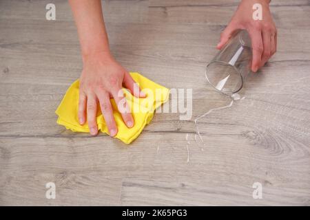 Vetro di acqua caduto su laminato, acqua versato sul pavimento. Foto Stock