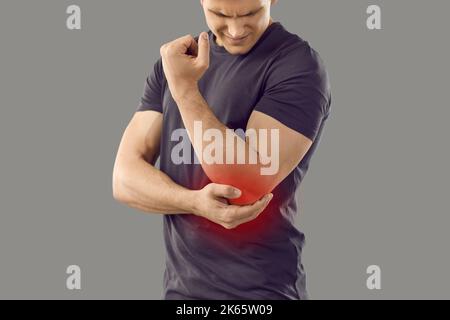 Giovane uomo che ha artrite o lesioni al braccio dolore sensazione e tenendo la mano sul gomito Foto Stock