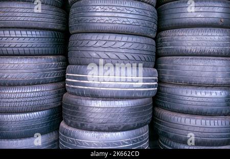 I pneumatici usati e vecchi vengono impilati nell'officina di riparazione pneumatici Foto Stock