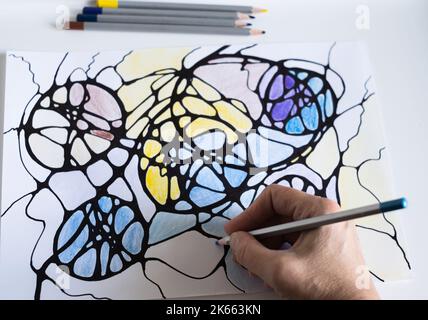 Una donna disegna un disegno neurografico su carta con matite a colori. L'arte Neurografica è un modo semplice per lavorare con la mente subcosciente attraverso il disegno. Foto Stock