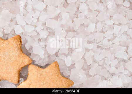 Vista dall'alto dei biscotti di pan di zenzero di Natale a forma di stella su sfondo sfocato di pezzi di ghiaccio con spazio per la copia del testo di saluto. Foto Stock