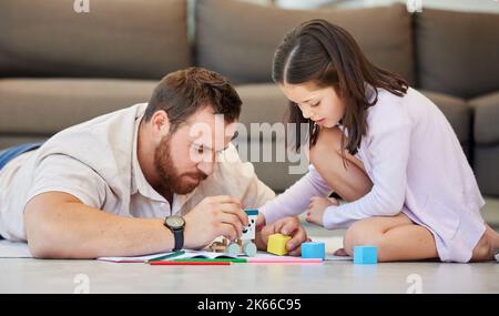 Padre e figlia giocano insieme a casa. Papà e figlia costruendo blocchi di legno. Progetto di risoluzione o di messa insieme di genitori e figli Foto Stock