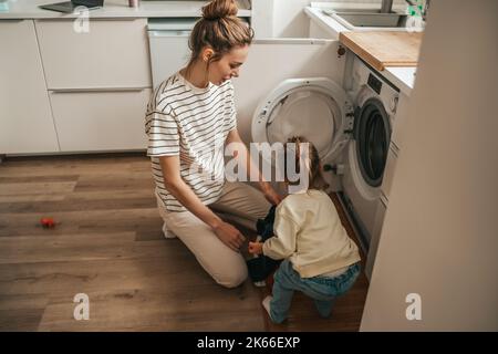 Madre e figlia caricano gli articoli nella rondella Foto Stock