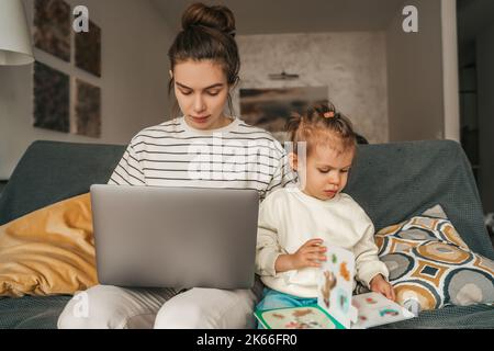 Madre e bambino freelance impegnati seduti sul divano in camera Foto Stock