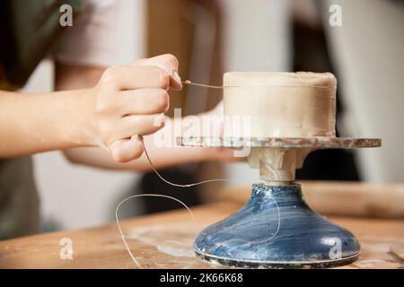 Mani di primo piano di ceramista femminile che lavora presso lo studio di ceramica su ruota di ceramica. Prodotti artigianali. Persone creative, hobby e abilità Foto Stock