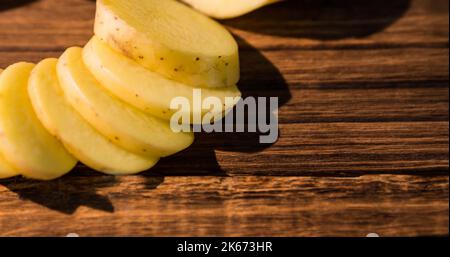 Primo piano ad angolo alto delle fette di patate crude su un tavolo di legno, spazio copia Foto Stock
