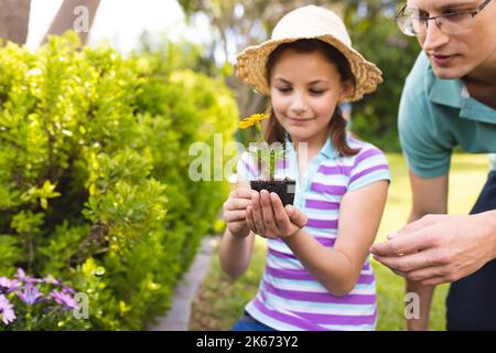 Il padre e la figlia caucasica trascorrono del tempo insieme nel giardino, piantando Foto Stock