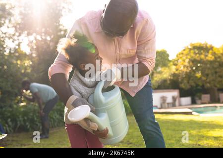 Padre e figlia afroamericana che trascorrono del tempo insieme in giardino Foto Stock