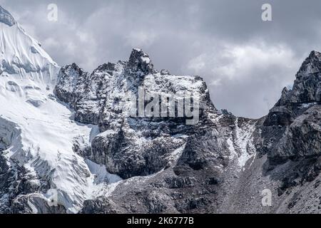 Le nuvole rivelano creste ricoperte di neve in una luce drammatica, in alto sopra l'Everest Way, durante il trekking fino al campo base dell'Everest Foto Stock