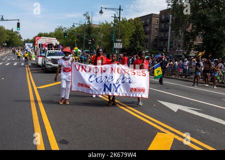 La Parata del West Indian Labor Day con persone in possesso di un poster "Union Nurses Care for NY" sulla strada Foto Stock