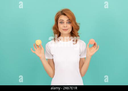 donna stupita tenere dolce macaron biscotto francese su sfondo blu Foto Stock