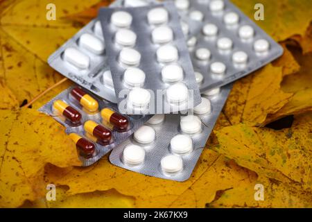 Variazione di pillole su foglie di acero giallo, confezioni di farmaci. Farmacia, antidepressivi, vitamina C per l'immunità in autunno stagione influenzale Foto Stock