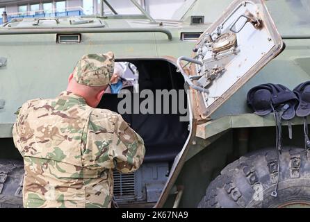 Militare vicino a un veicolo militare di terra corazzato russo Foto Stock