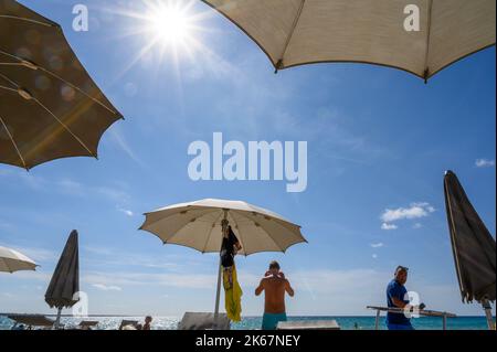 Bagnanti e beachgoer con lettini e ombrelloni sulla spiaggia di Sottovento a sud della città di Gallipoli, Puglia, Italia. Foto Stock