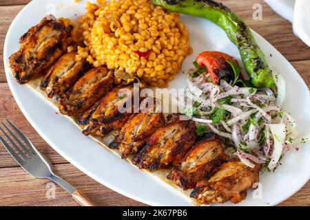 Spiedini di pollo grigliati su sfondo di legno. Prodotti alimentari turchi. Primo piano Foto Stock