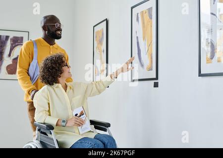 Donna felice con disabilità visitando la galleria d'arte con il giovane Foto Stock