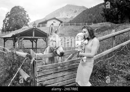 Mamma con sua figlia che si diverte al ranch fattoria e. Incontro con un asino - concetto di PET Therapy in campagna con Asino nella fattoria didattica - animale domestico il Foto Stock