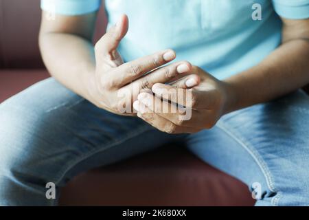 uomo che soffre dolore in mano seduto sul divano Foto Stock
