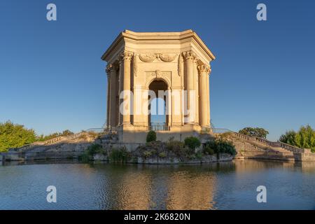 Inizio estate mattina vista dello storico edificio in pietra torre d'acqua e la piscina nel caratteristico giardino Promenade du Peyrou, Montpellier, Francia Foto Stock