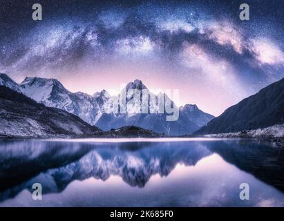 Arco di Via Lattea sulle montagne innevate e sul lago di notte Foto Stock