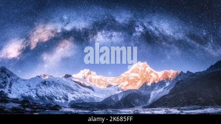 Arco di Via Lattea sulle montagne innevate nella notte stellata d'inverno. Foto Stock