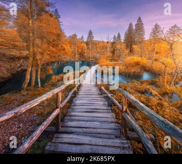 Sentiero in legno nella foresta di arance nei laghi di Plitvice, Croazia al tramonto Foto Stock