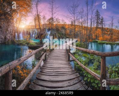 Cascata e sentiero in legno nella foresta arancione dei laghi di Plitvice Foto Stock