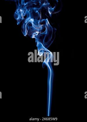 Un sottile flusso di fumo blu si arriccia e si innalza in modo spettacolare su uno sfondo nero Foto Stock