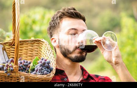 Giovane uomo che ama il gusto del vino rosso in azienda vinicola all'aperto - concetto di esperienza con sommelier professionale degustazione di bio prodotto al momento della vendemmia - o. Foto Stock
