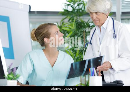 infermiera di sesso maschile che parla con un medico senior Foto Stock
