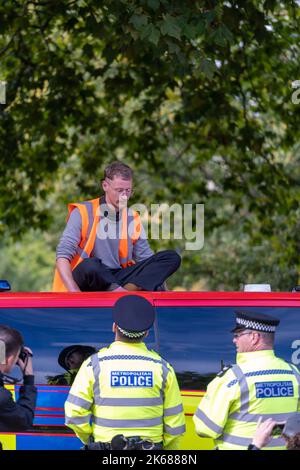 Due sostenitori di Just Stop Oil sono saliti sulla cima di un pulmino della polizia metropolitana fuori da Horse Guards Road a Londra mercoledì (12 ottobre) in un periodo in corso Foto Stock