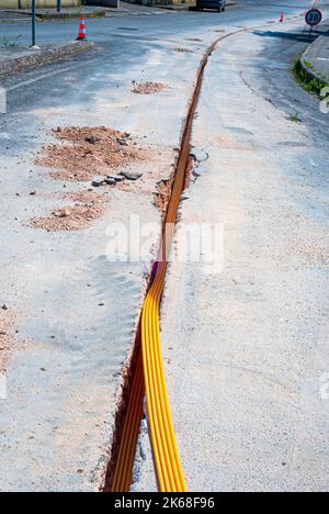 Il lavoratore inserisce cavi in fibra ottica interrati in una micro trincea Foto Stock