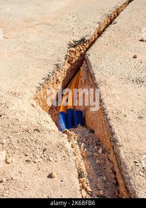 Il lavoratore inserisce cavi in fibra ottica interrati in una micro trincea Foto Stock