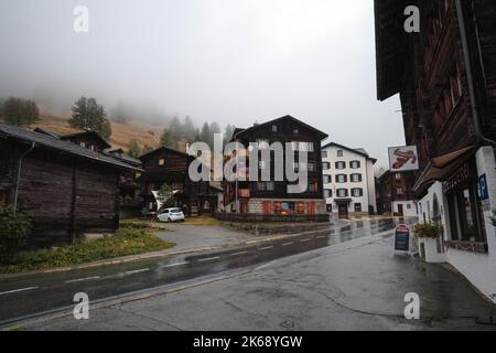 Antico granaio di raccard svizzero tradizionale in legno su pali di pietra nel vecchio quartiere di Hinterdorf di Zermatt Svizzera, tempo piovoso. Foto Stock