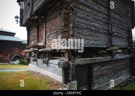 Antico granaio di raccard svizzero tradizionale in legno su pali di pietra nel vecchio quartiere di Hinterdorf di Zermatt Svizzera, tempo piovoso. Foto Stock