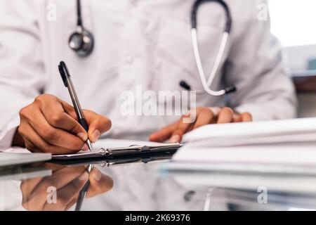 medico indiano che indossa uniforme prendendo appunti in documenti medici Foto Stock